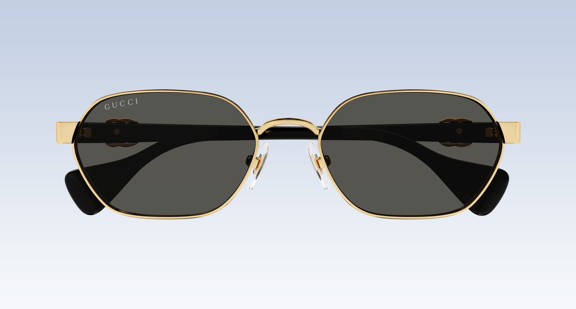 Gucci GG1593S 001 Gold Black Square Aviator Sunglasses with a gold-tone metal frame, dark gray lenses, and black temple tips, shown from the front against a light blue gradient background.