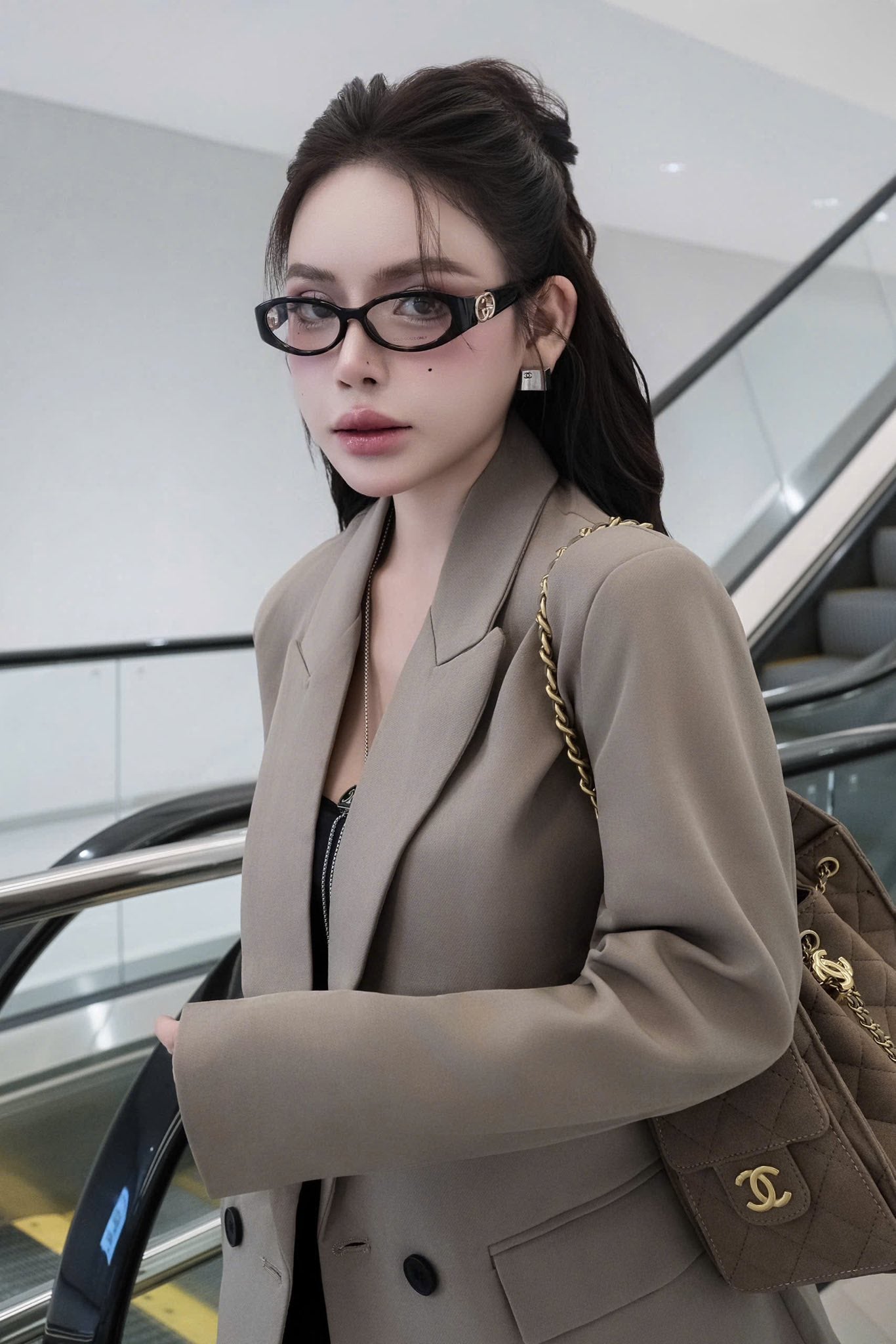Woman wearing Gucci GG16930-001 Oval Eyeglasses in a beige blazer with a Chanel handbag in an indoor setting