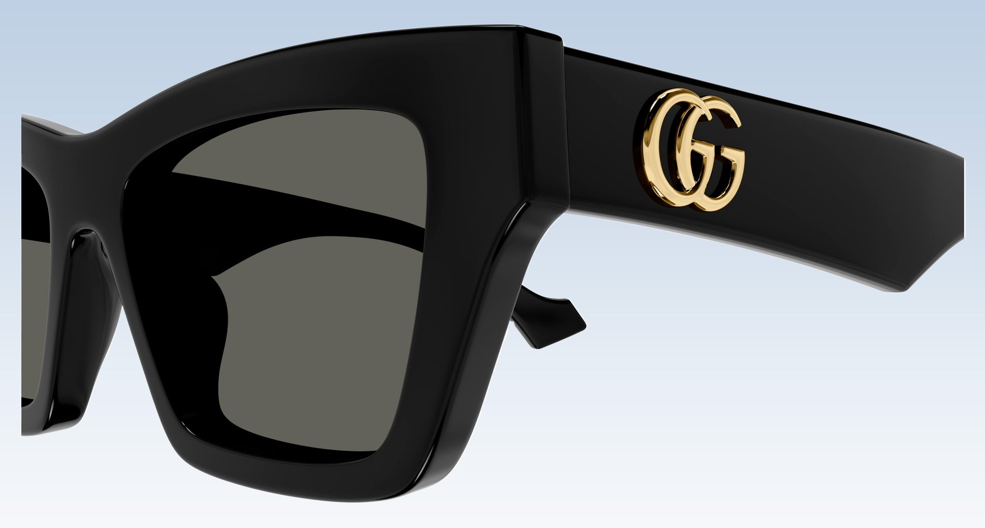 Gucci GG1753S 001 Black Square Sunglasses with a glossy black frame, dark gray lenses, and a gold interlocking GG logo on the temple arm, shown against a light blue gradient background.