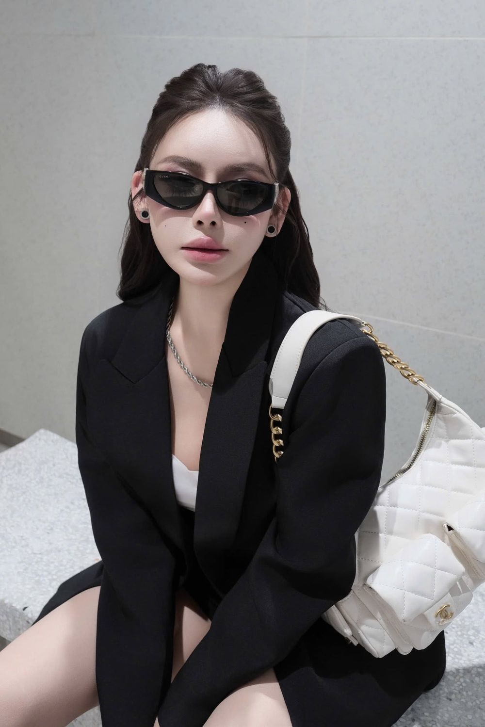 women wearing Gucci GG1824S 001 Black Cat-Eye Sunglasses in black blazer and holding a white chanel bag
