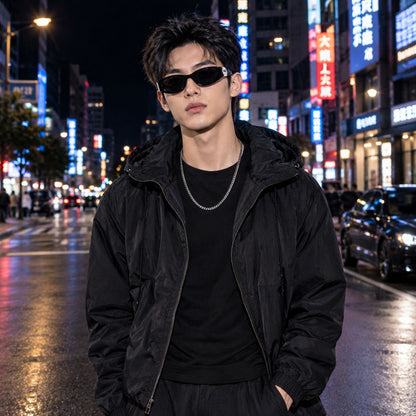 A man wearing a black hooded puffer jacket, black t-shirt, black pants, and Gucci GG1824S 001 Black Cat-Eye Sunglasses stands on a wet city street at night with neon lights in the background.