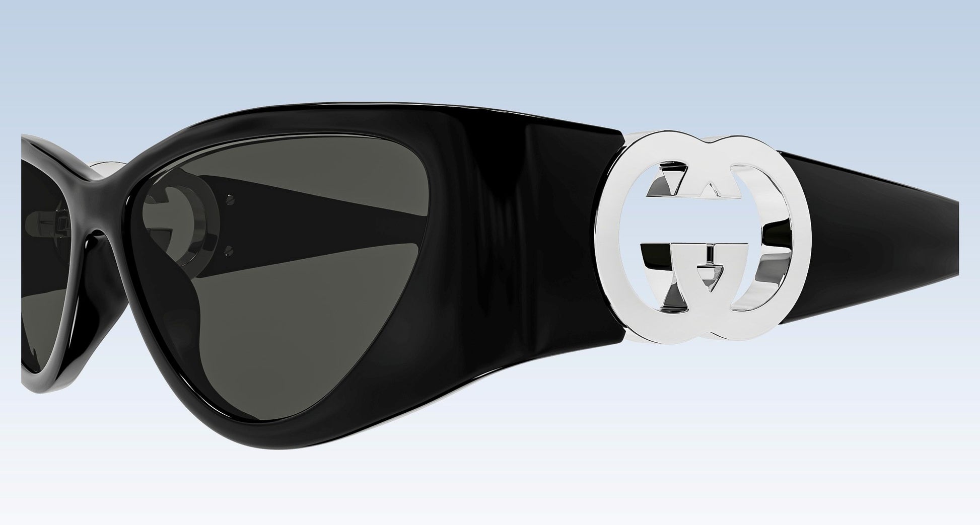 Gucci GG1824S 001 Black Cat-Eye Sunglasses with a glossy black frame, dark tinted lenses, and a prominent silver interlocking GG logo on the temple arm, shown against a light blue gradient background.
