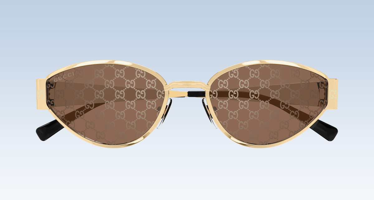 Gucci GG1853S 003 GG double-G patterned brown sunglasses with gold-tone metal frames and black temple tips, shown against a light blue gradient background.