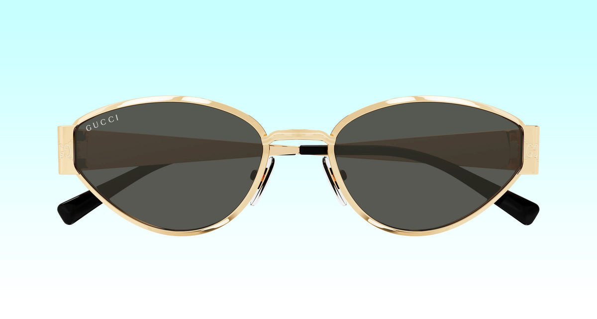 Gucci GG1853S 001 Gold Butterfly Sunglasses with a gold-tone metal frame and dark gray lenses, shown against a light blue gradient background.