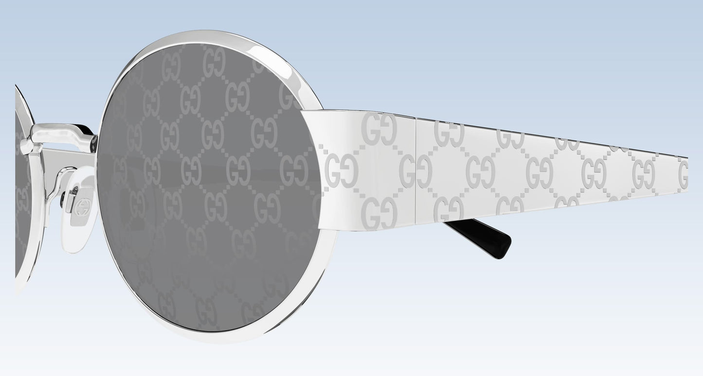 Gucci GG1854S 002 Silver Round Sunglasses with silver-tone metal frames, gray GG monogram lenses, and white temples featuring the signature GG pattern, shown on a light blue gradient background.