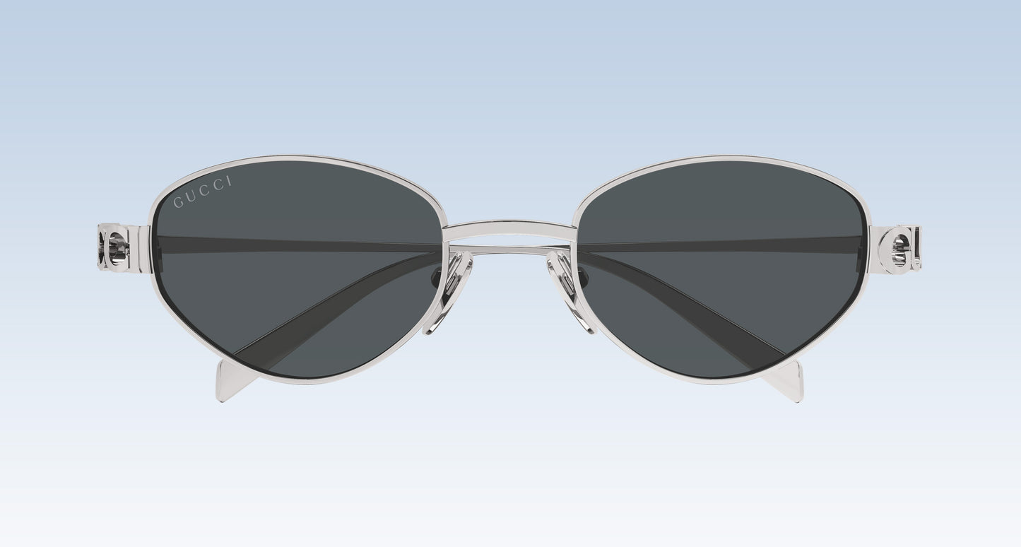 Gucci GG1935S 001 Silver Round Oval Sunglasses with a silver-tone metal frame and dark gray lenses, shown against a light blue gradient background.