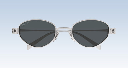 Gucci GG1935S 001 Silver Round Oval Sunglasses with a silver-tone metal frame and dark gray lenses, shown against a light blue gradient background.