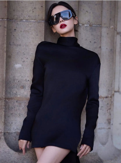 A woman wearing a black long-sleeve mock-neck mini dress and Gucci GG1950S 001 Black Shield Sunglasses, posing against a textured stone wall.