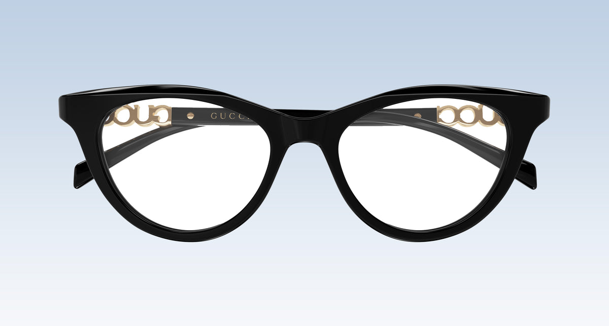 Gucci GG2034O 001 Black Cat-Eye Eyeglasses in glossy black acetate with gold-tone metal details on the inner rims, shown against a light blue gradient background.