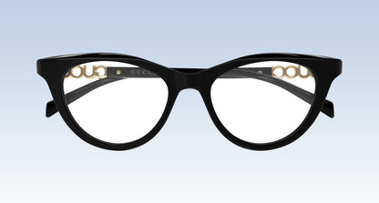 Gucci GG2034O 001 Black Cat-Eye Eyeglasses in glossy black acetate with gold-tone metal details on the inner rims, shown against a light blue gradient background.