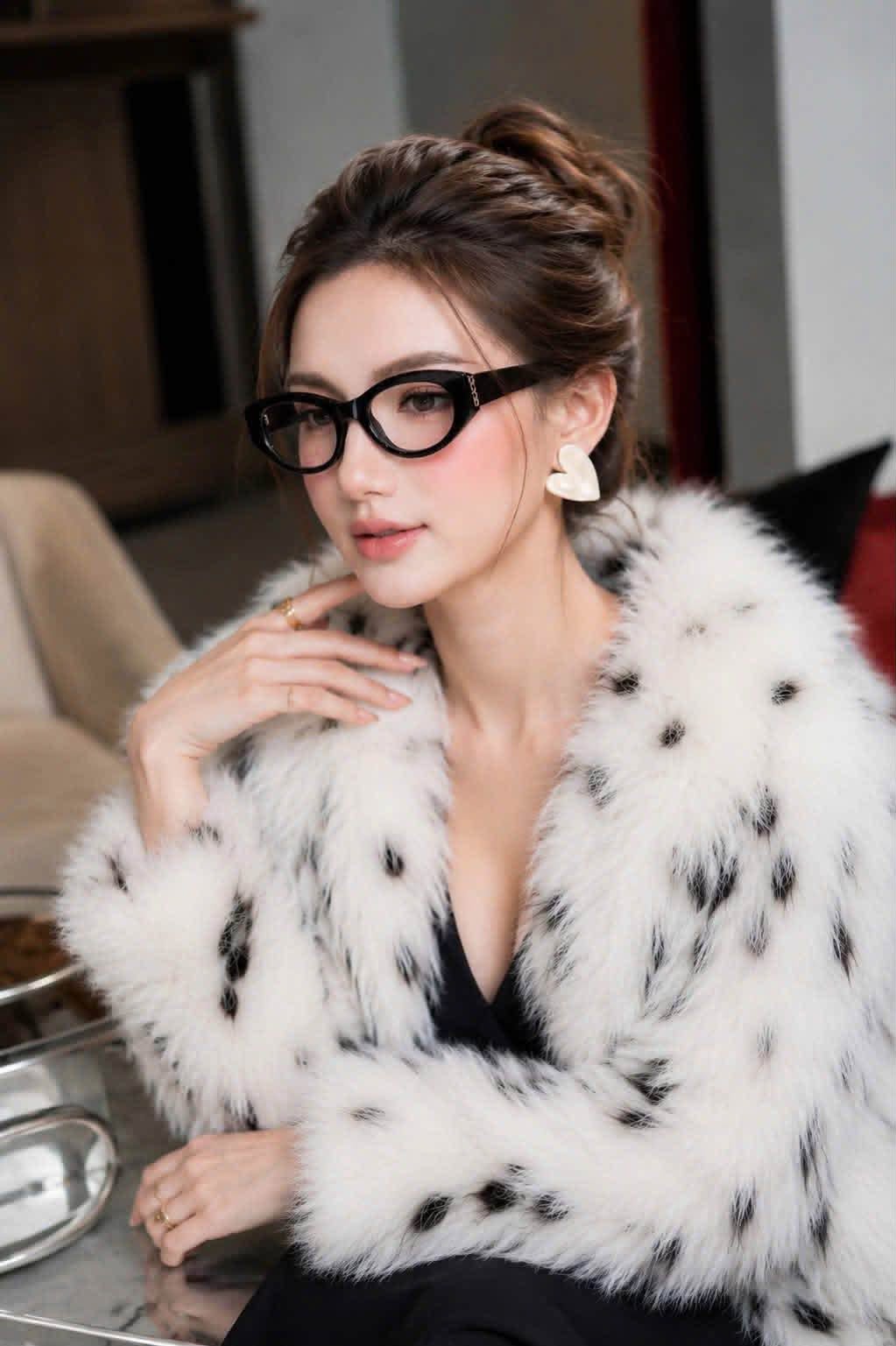 A woman wearing Gucci GG2041O-001 Black Oval Eyeglasses and a white faux fur jacket with black spots, posing indoors.