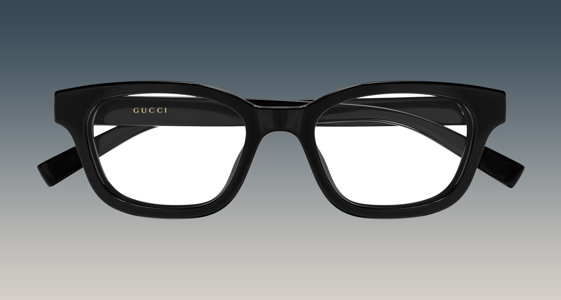Gucci GG2103OL-001 Black Rectangular Eyeglasses with a thick, rounded rectangular frame and gold logo lettering on the inner left frame, shown against a gradient gray background.