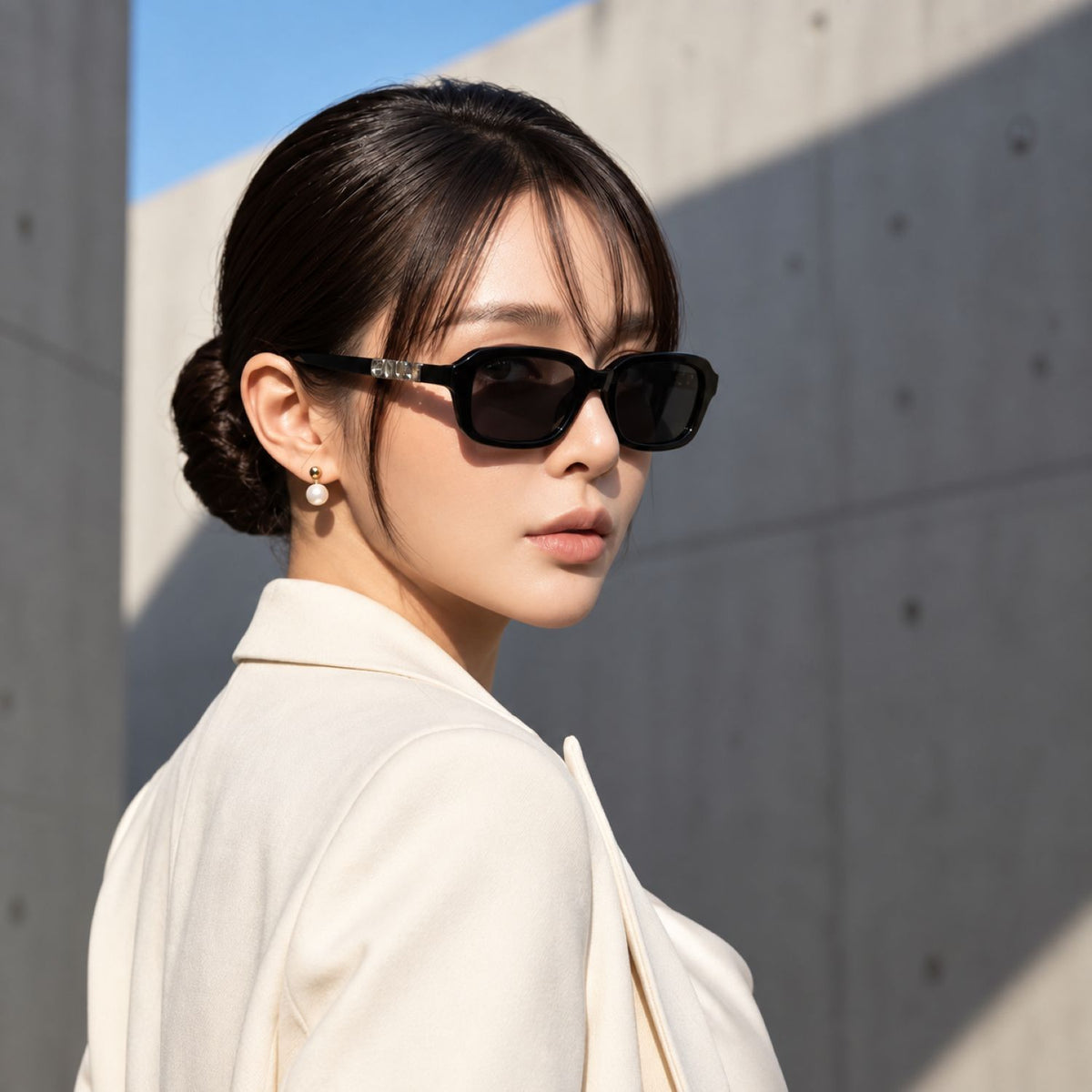Woman wearing Gucci GG2152S 001 Black Rectangular Sunglasses in white blazer with pearl earrings