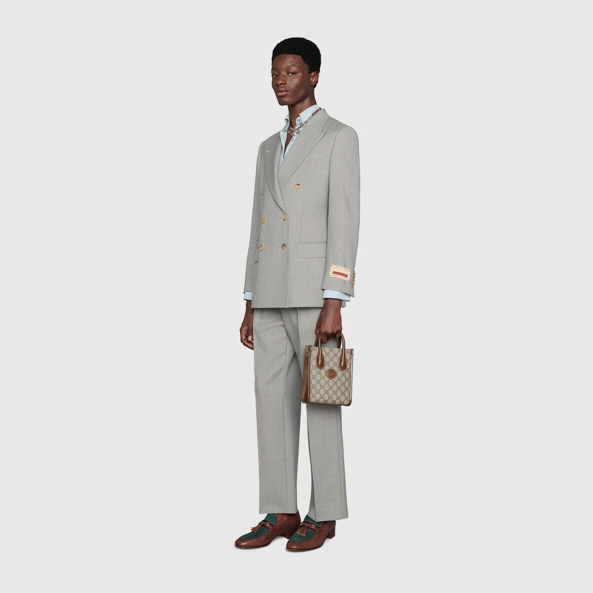Man wearing a gray suit with a Gucci Interlocking G Mini Tote Bag 671623 92TCG 8563 on a white background