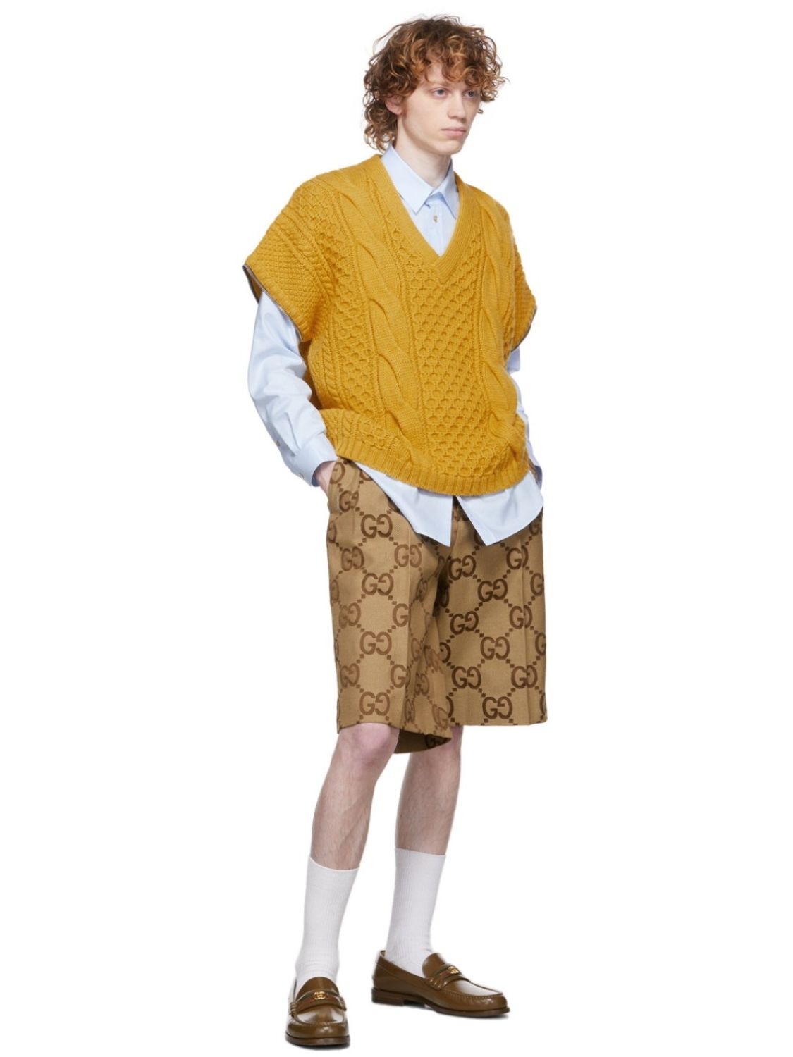 Person wearing a mustard yellow sweater vest over a white shirt with Gucci Jumbo GG Canvas Short In Beige & Ebony 673181 ZAHT6 2580  on a white background