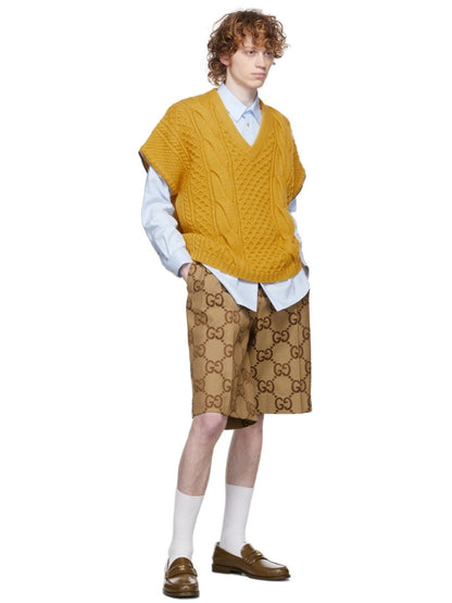 Person wearing a mustard yellow sweater vest over a white shirt with Gucci Jumbo GG Canvas Short In Beige & Ebony 673181 ZAHT6 2580  on a white background