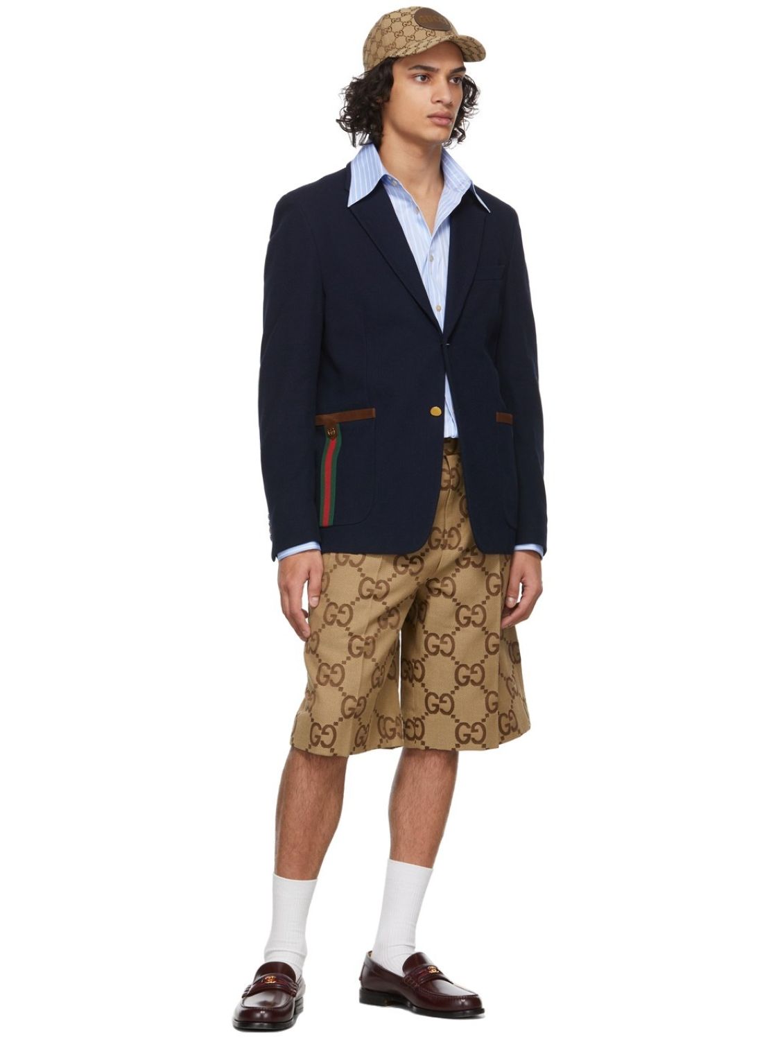 Person wearing a navy blazer, white shirt, and Gucci Jumbo GG Canvas Short In Beige & Ebony 673181 ZAHT6 2580  with a pattern on a white background