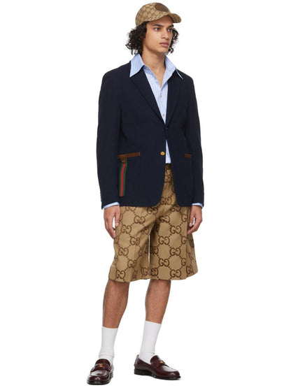 Person wearing a navy blazer, white shirt, and Gucci Jumbo GG Canvas Short In Beige & Ebony 673181 ZAHT6 2580  with a pattern on a white background