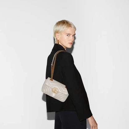 Woman carrying a Gucci GG Marmont Small Shoulder Bag Light Grey 446744 AABZC 1712 against a plain background
