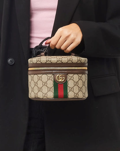 Person holding a Gucci Mini Ophidia Cosmetic Case 627463-96IWG-8745 with a visible logo and color stripe.
