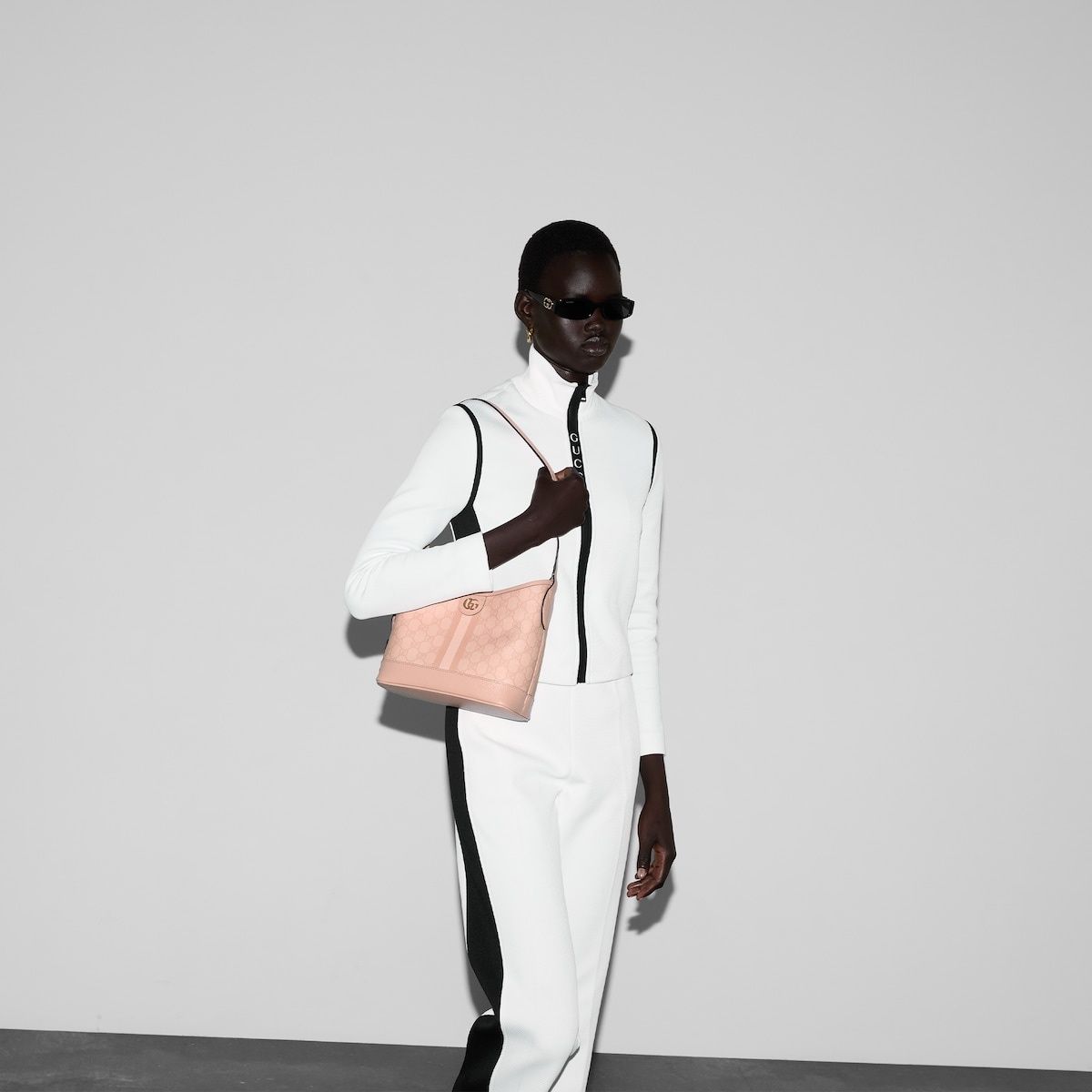 Person wearing a white outfit with a Gucci Ophidia Small Bucket Shoulder Bag Dusty Pink 781402-FAD1P-6241 against a plain background