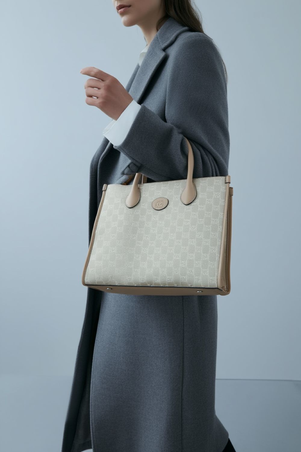 Person holding a Gucci Small Tote Bag With Interlocking G Beige 659983 UULBT 9683 with a plain background