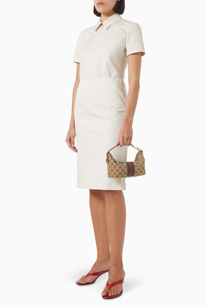Woman wearing a white dress holding a Gucci Vanity Mini Bag Beige & Brown GG Canvas 861775 FAFUF 9870 on a white background