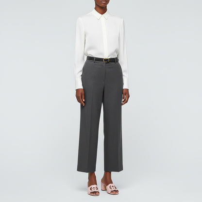 Person wearing a white shirt and gray pants with Gucci Women’s Slide Sandal Interlocking G Pink 782413 AAAZG 5908 on a light gray background