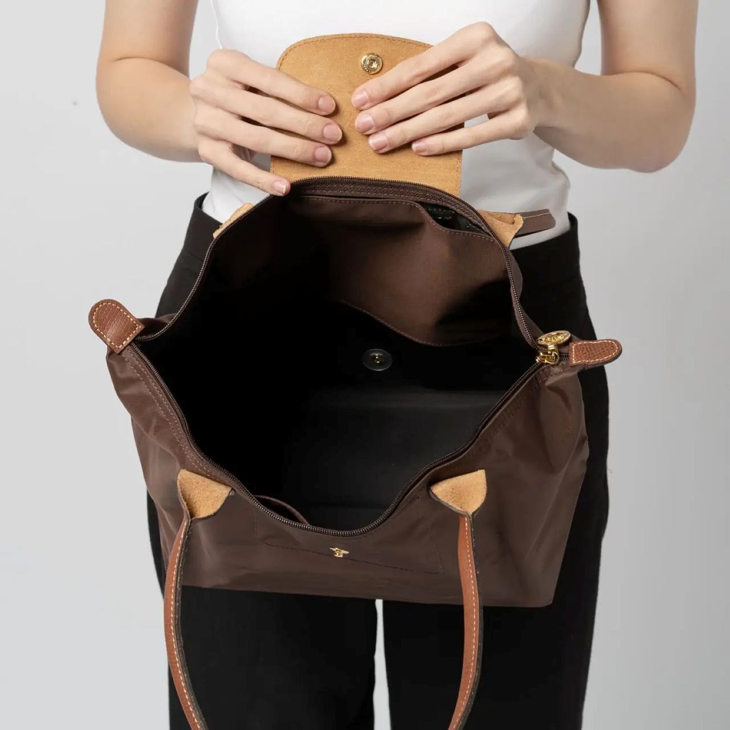 Open Longchamp Le Pliage Original M Tote Bag Ebony L2605089P81 with gold accents held by a person against a plain background