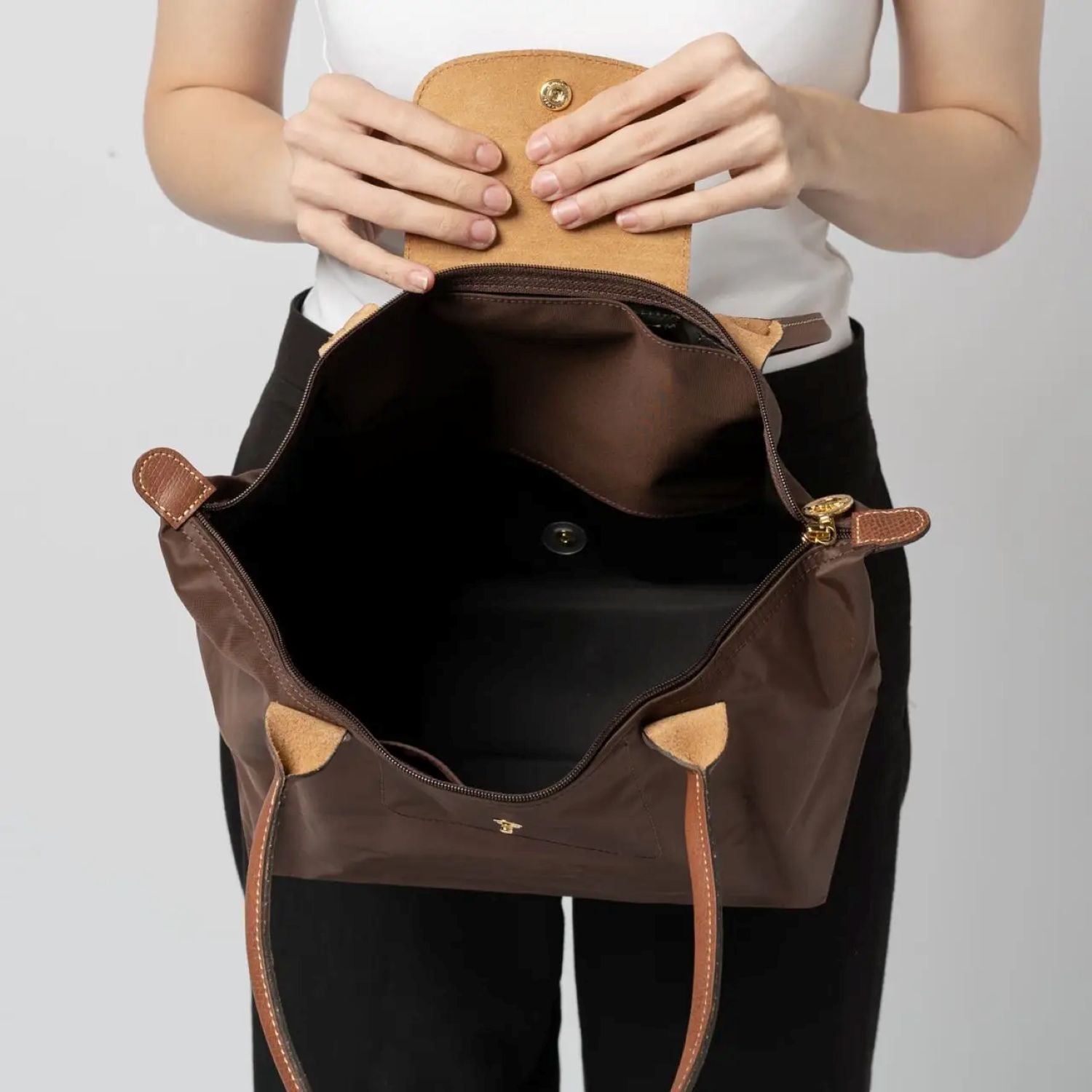 Open Longchamp Le Pliage Original M Tote Bag Ebony L2605089P81 with gold accents held by a person against a plain background