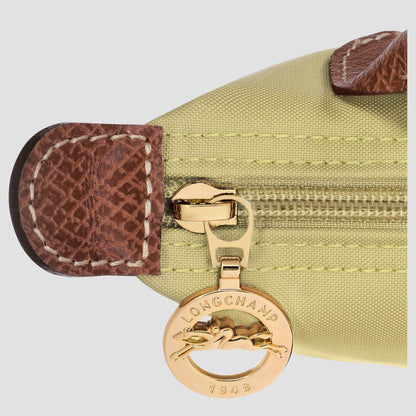Close-up of a gold Longchamp charm on a green bag with brown leather accents.