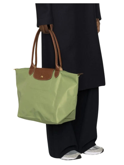 Person holding a Longchamp Le Pliage Original Tote Bag L – Lichen L1899089P77 with brown handles against a white background