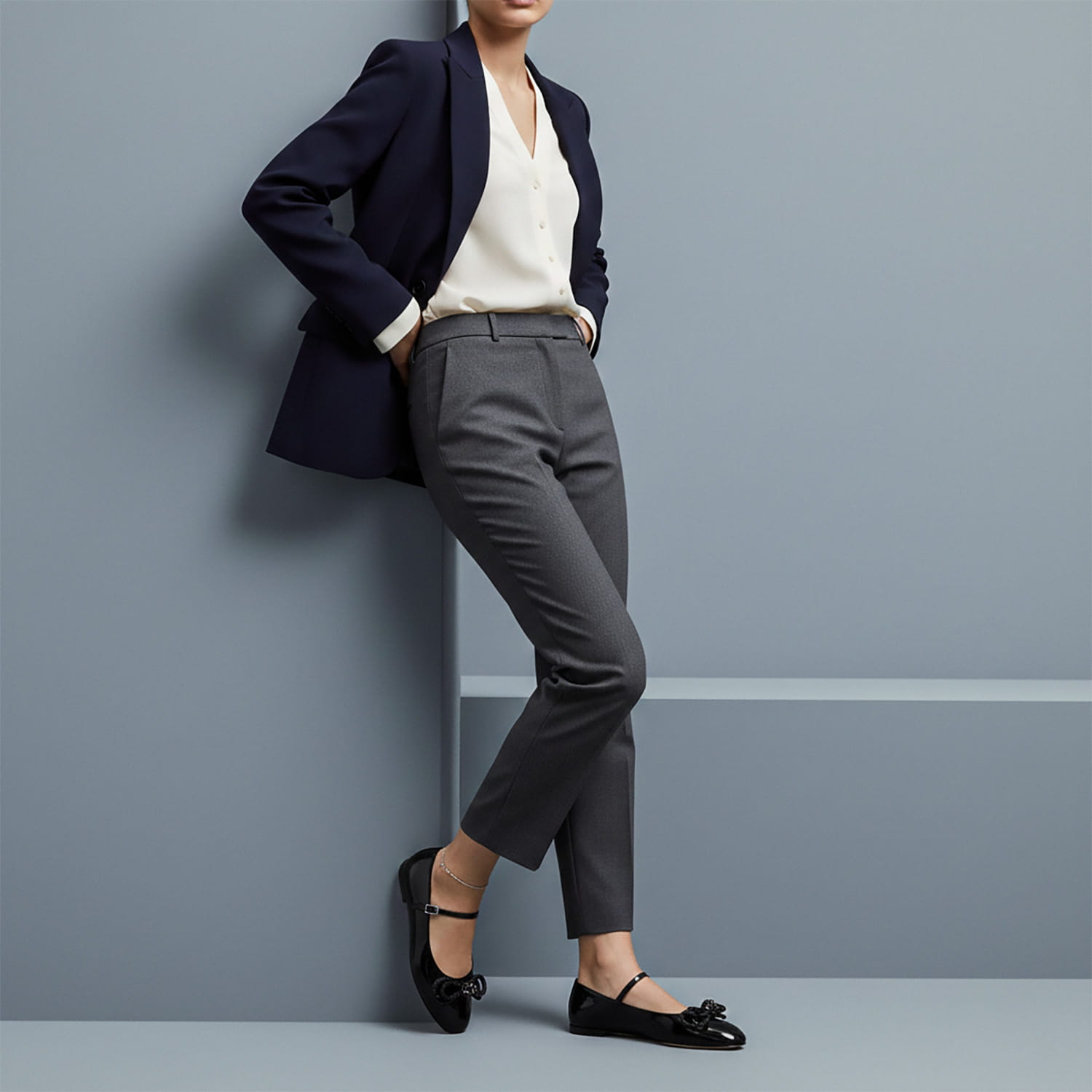 Person wearing a navy blazer, white shirt, gray pants, and MACH & MACH Double Bow Black Patent Ballet Flat against a gray wall.