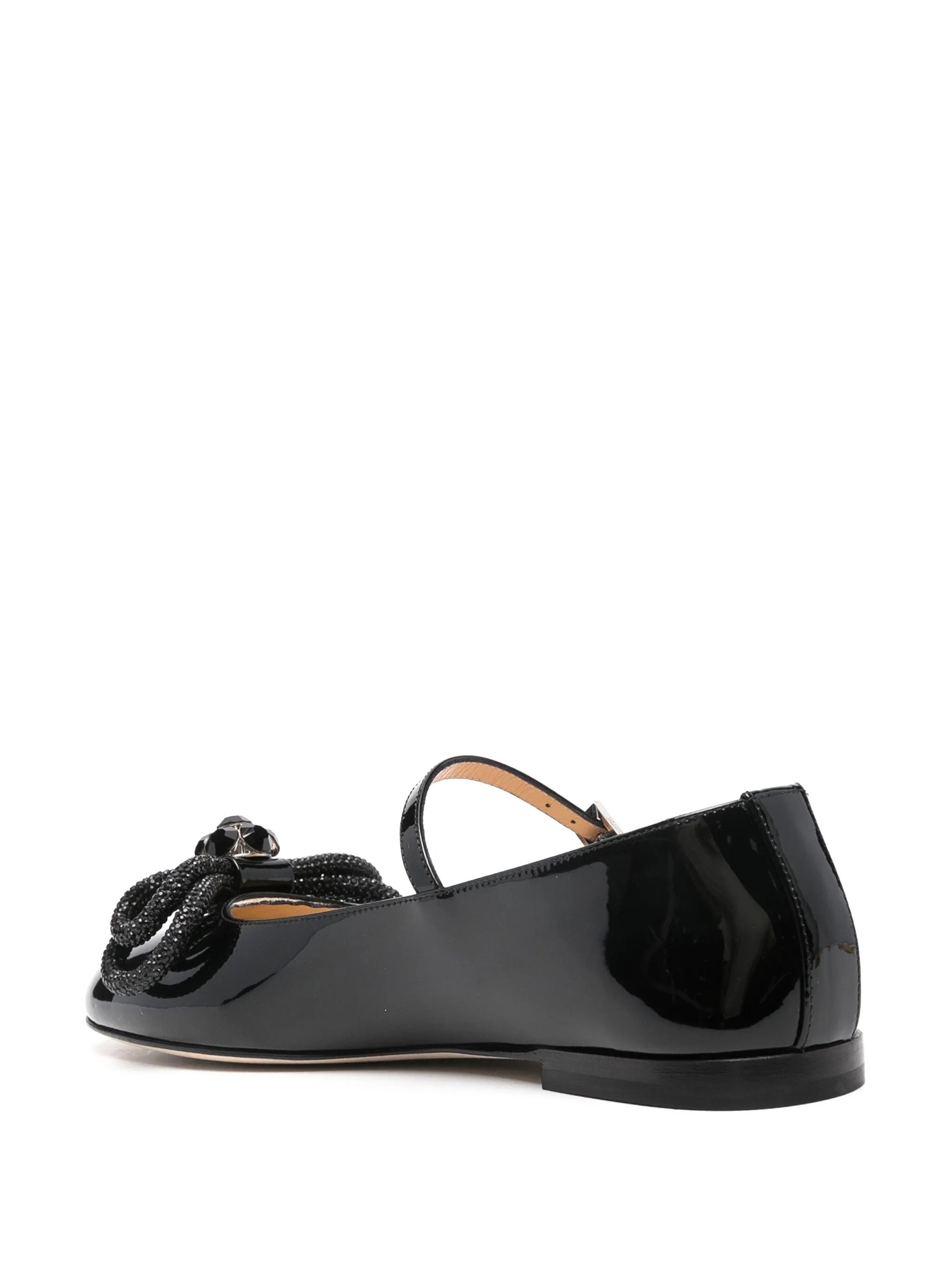 Black flat shoe with a decorative element on a white background