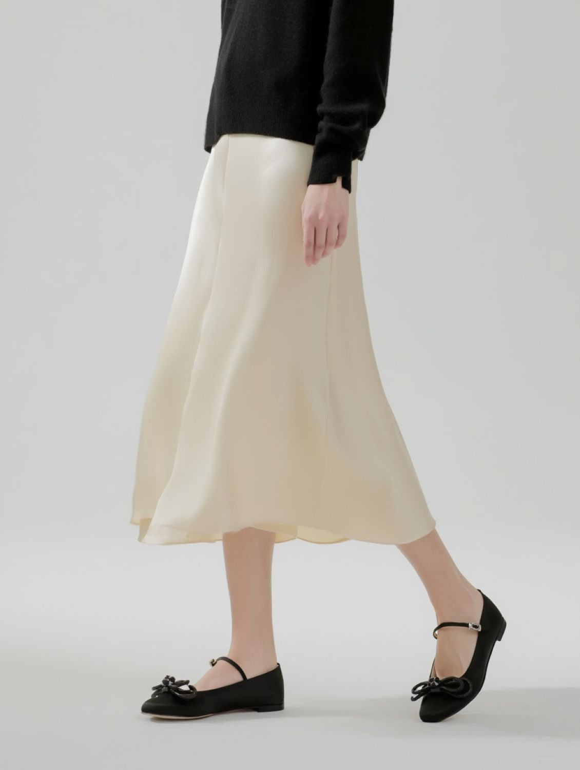 Person wearing a beige skirt and MACH & MACH Double Bow Black Satin Ballerinas on a plain background