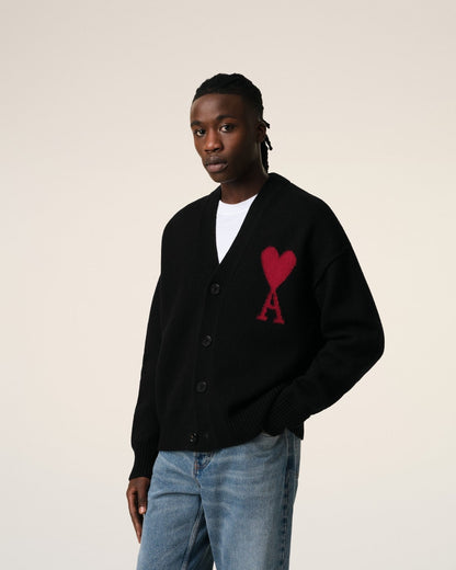 Person wearing a Merino Wool Ami De Coeur Cardigan Black/Red BFUKC006.018.009 with a red heart design on a beige background
