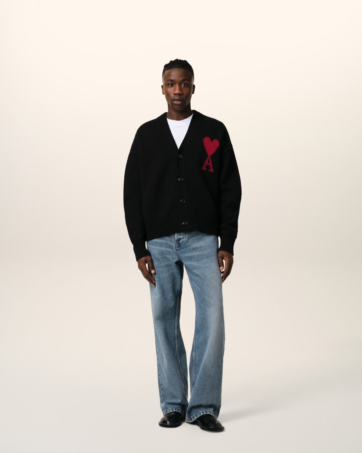 Person wearing a Merino Wool Ami De Coeur Cardigan Black/Red BFUKC006.018.009 with a red heart design and blue jeans on a white background