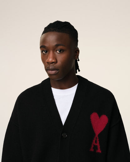 Person wearing a Merino Wool Ami De Coeur Cardigan Black/Red BFUKC006.018.009 with a red heart and letter 'A' design on a beige background