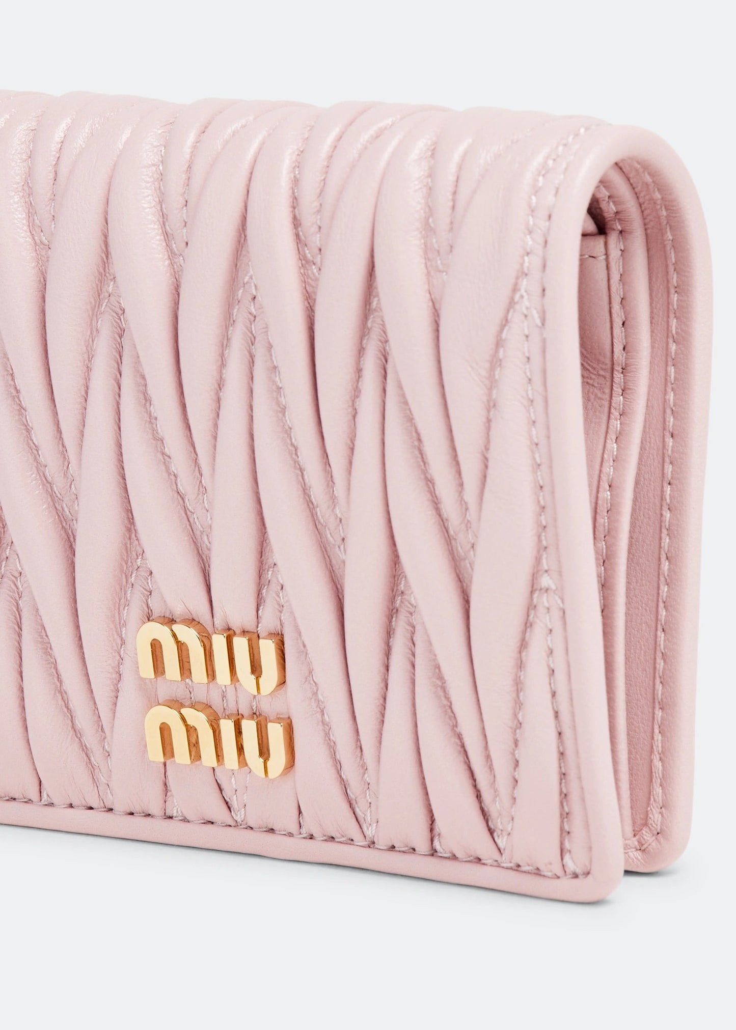 Pink quilted wallet with gold 'miu miu' logo on a light gray background