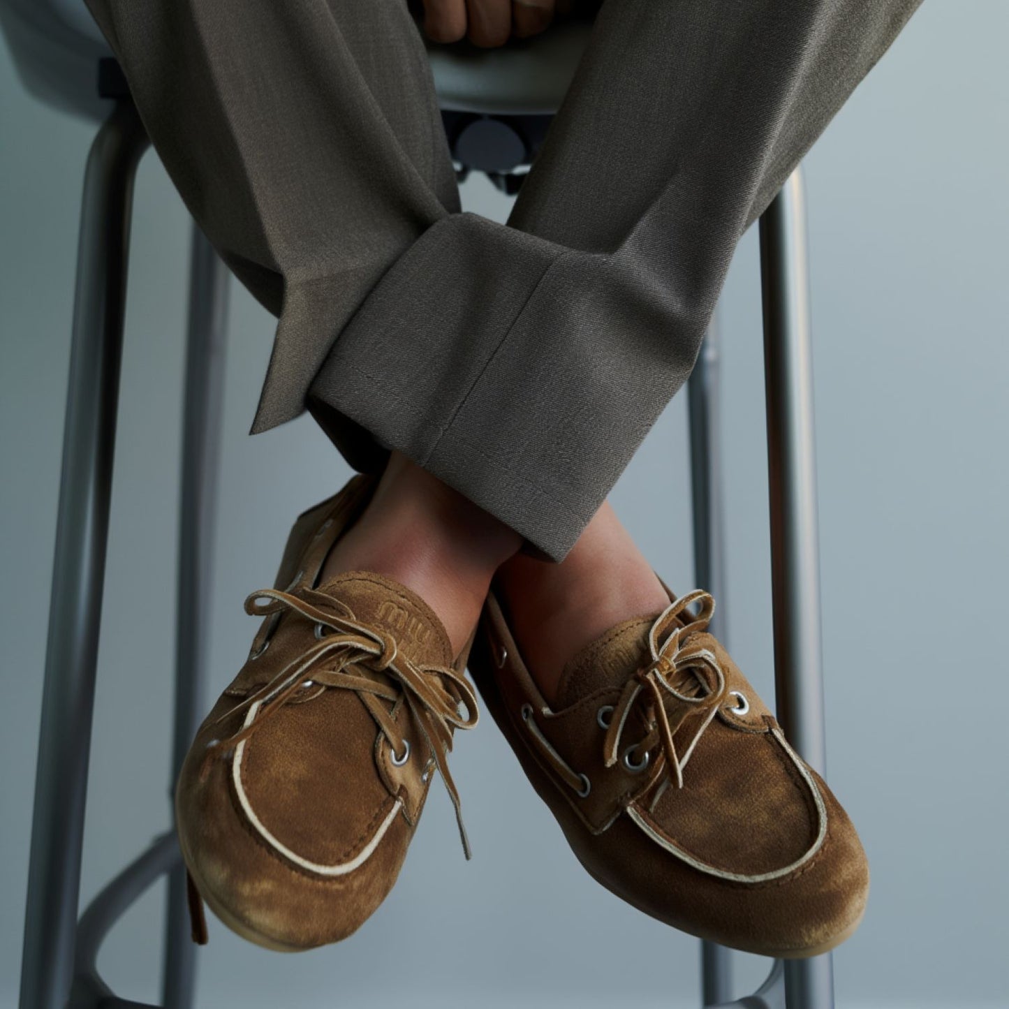 Miu Miu Faded Unlined Suede Loafers – Cinnamon 5D123E_Z5O_F0401_F_D005 with white laces worn by a person sitting on a stool.