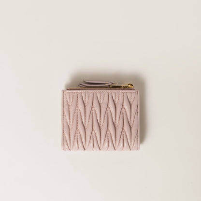 Behind Miu Miu Matelassé Nappa Leather Small Wallet Powder Pink 5ML024_AFPP_F0236 with gold zipper on a beige background