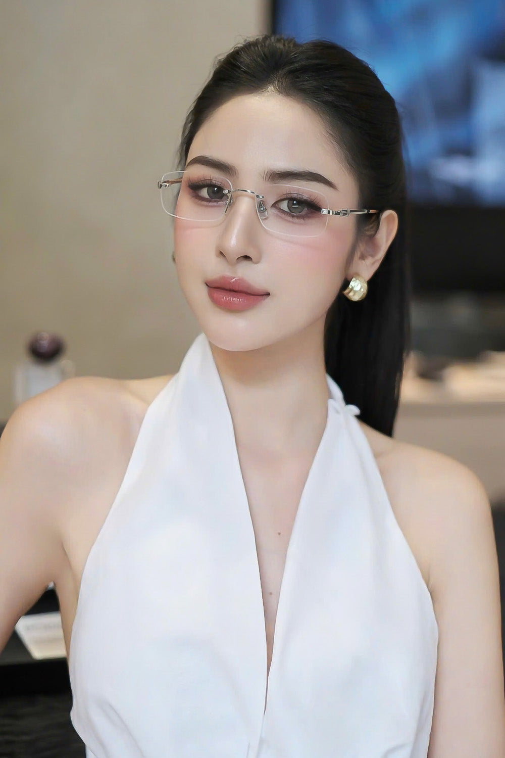 Woman wearing Miu Miu MU 50YV 1BC1O1 Rimless Silver Eyeglasses and a white top in an indoor setting
