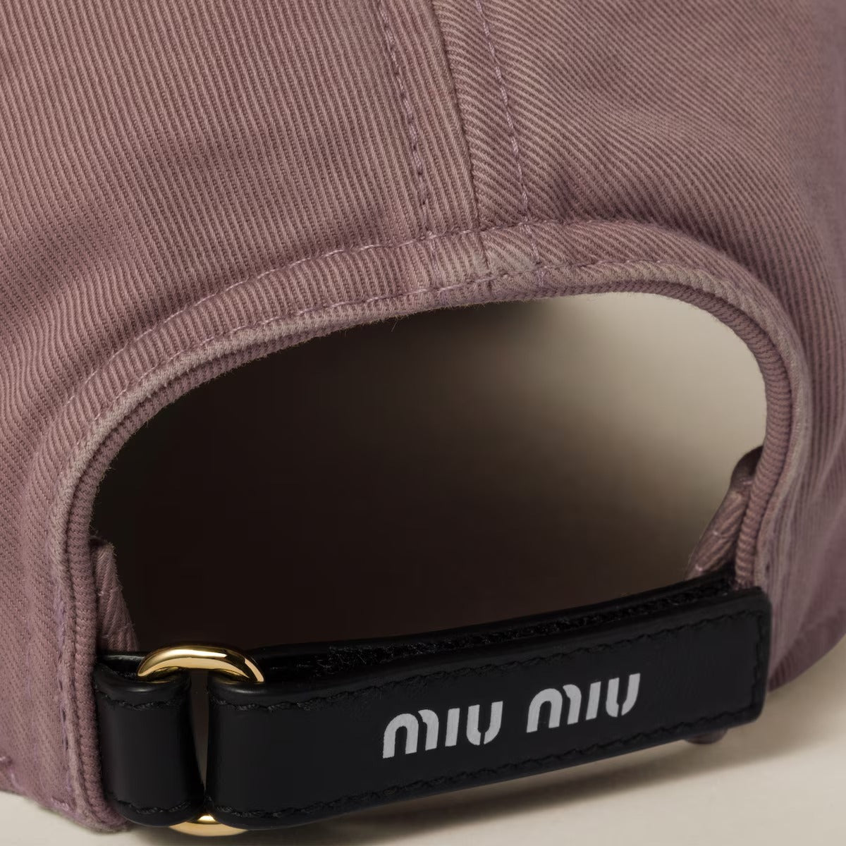 Close-up of Miu Miu Raspberry Drill Baseball Cap 5HC370 2CR2 F0590 with a black strap displaying 'miu miu' on a neutral background