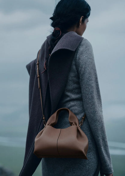 Person wearing a gray coat and carrying a Polène Numéro Neuf Mini Edition Textured Root on a foggy day.