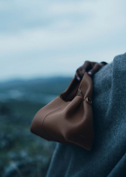 Polène Numéro Neuf Mini Edition Textured Root draped over a shoulder with a blurred natural background