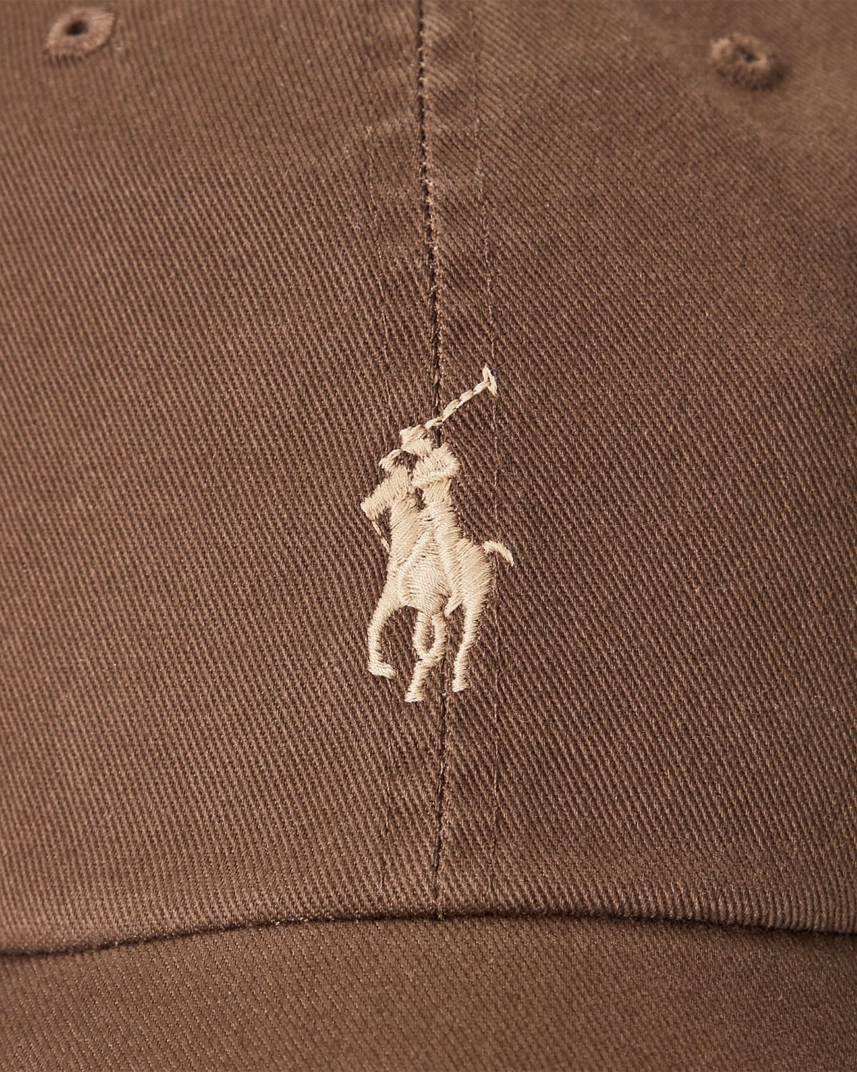 Close-up of a brown cap with a white embroidered logo on a brown background