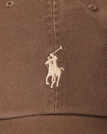 Close-up of a brown cap with a white embroidered logo on a brown background