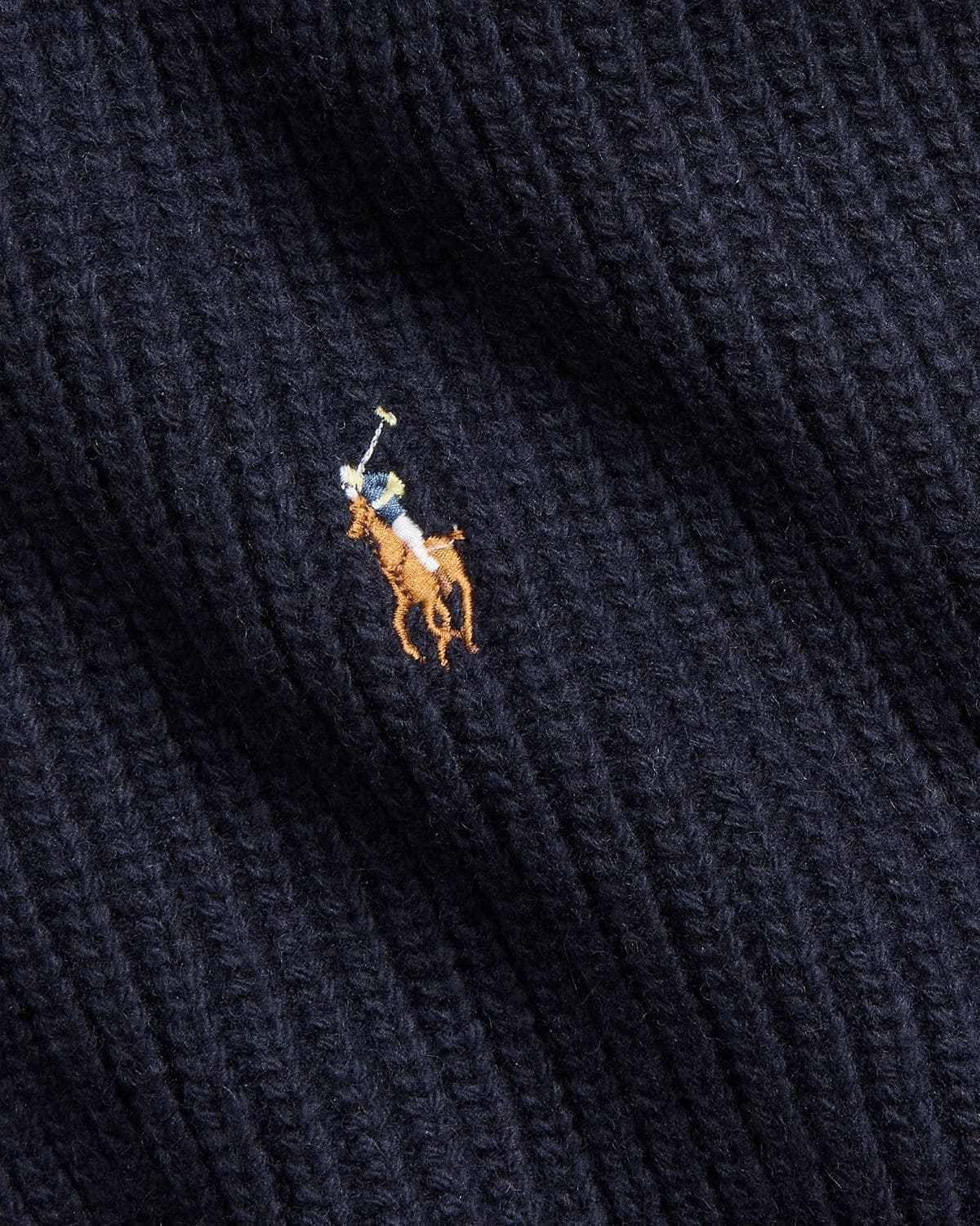 Close-up of a navy blue fabric with a embroidered logo featuring a polo player and horse.