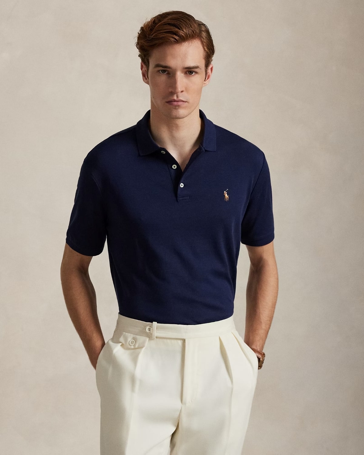 Man wearing a Polo Ralph Lauren Men’s Soft Cotton Polo Shirt Classic Fit – Refined Navy 710666999003 with a logo on a beige background