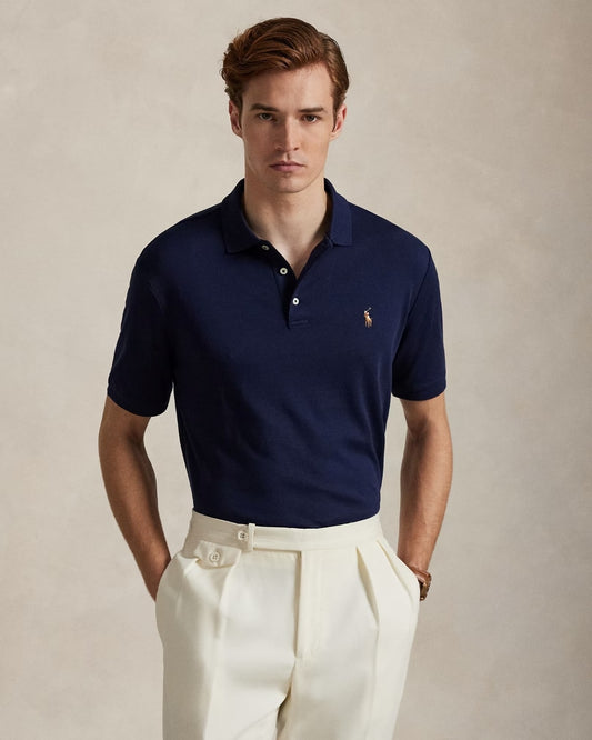 Man wearing a Polo Ralph Lauren Men’s Soft Cotton Polo Shirt Classic Fit – Refined Navy 710666999003 with a logo on a beige background